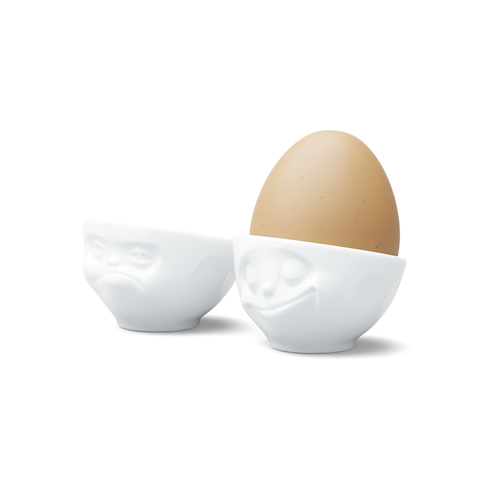 Set of two egg cups in white from the porcelain product family of fun dishware by FIFTYEIGHT Products. Set features two egg cups in white, featuring 'Happy' and 'Hmpff' facial expressions. Dishwasher and microwave safe bowls. Shipped in exclusively designed gift box.