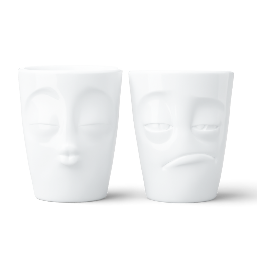 Set of two coffee mugs without handles in white from the porcelain product family of fun dishware by FIFTYEIGHT Products. Each offering 11 oz capacity. Dishwasher and microwave safe coffee cups with a 'snoozy' and one with a 'kissing' facial expression. Shipped in exclusively designed gift box.