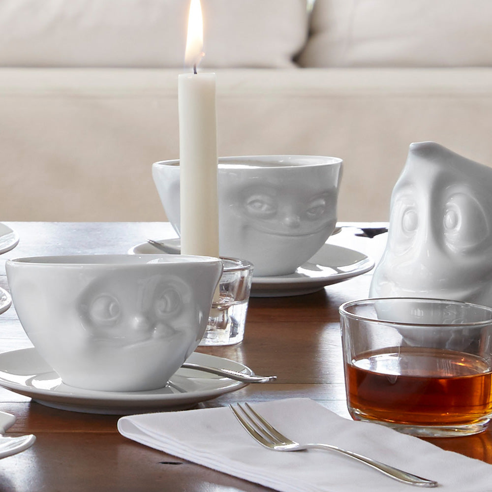 Premium porcelain coffee cup with saucer in white from the porcelain product family of fun dishware by FIFTYEIGHT Products. Offers 6.5 oz capacity and comes with a matching saucer. Dishwasher and microwave safe cup with a 'grinning' facial expression. Shipped in exclusively designed gift box.