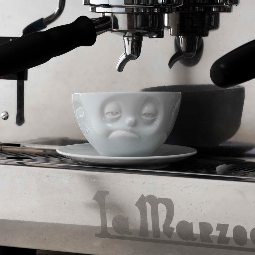 Premium porcelain coffee cup with saucer in white from the porcelain product family of fun dishware by FIFTYEIGHT Products. Offers 6.5 oz capacity and comes with a matching saucer. Dishwasher and microwave safe cup with a ''snoozy' facial expression. Shipped in exclusively designed gift box.