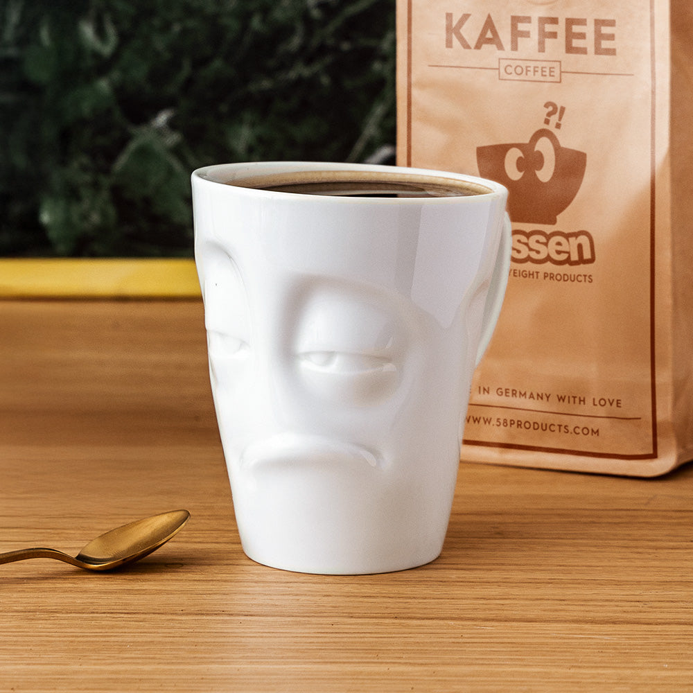 Premium porcelain coffee mug with handle from the popular product family of fun dishware by FIFTYEIGHT Products. Offers 11 oz capacity for serving coffee, tea, latte, matcha, soup and more. Dishwasher and microwave safe cup with a 'snoozy' facial expression. Shipped in exclusively designed gift box.