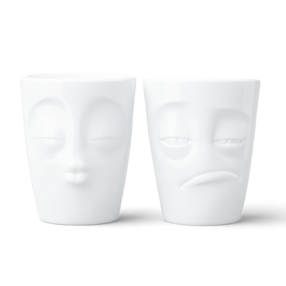 Set of two coffee mugs without handles in white from the porcelain product family of fun dishware by FIFTYEIGHT Products. Each offering 11 oz capacity. Dishwasher and microwave safe coffee cups with a 'snoozy' and one with a 'kissing' facial expression. Shipped in exclusively designed gift box.