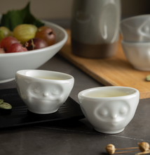 Load image into Gallery viewer, Set of two egg cups in white from the TASSEN product family of fun dishware by FIFTYEIGHT Products. Set features two egg cups in white, featuring &#39;kissing&#39; and &#39;dreamy&#39; facial expressions. Dishwasher and microwave safe bowls. Shipped in exclusively designed gift box.
