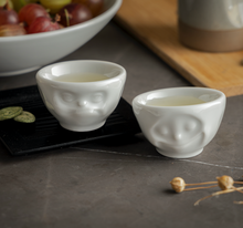 Load image into Gallery viewer, Set of two egg cups in white from the TASSEN product family of fun dishware by FIFTYEIGHT Products. Set features two egg cups in white, featuring &#39;Happy&#39; and &#39;Hmpff&#39; facial expressions. Dishwasher and microwave safe bowls. Shipped in exclusively designed gift box.
