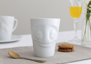 Coffee mug with 'cheery' facial expression and 11 oz capacity. From the TASSEN product family of fun dishware by FIFTYEIGHT Products. Tall coffee cup with handle in white, crafted from quality porcelain.