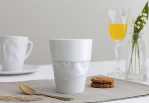 Coffee mug with 'grumpy' facial expression and 11 oz capacity. From the TASSEN product family of fun dishware by FIFTYEIGHT Products. Tall coffee cup with handle in white, crafted from quality porcelain.