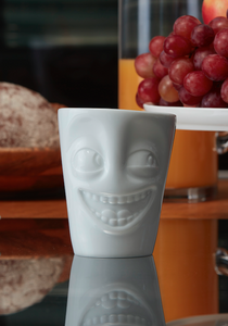 Coffee mug with 'joking' facial expression and 11 oz capacity. From the TASSEN product family of fun dishware by FIFTYEIGHT Products. Tall coffee cup with handle in white, crafted from quality porcelain.