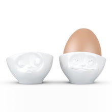 Load image into Gallery viewer, Set of two egg cups in white from the TASSEN product family of fun dishware by FIFTYEIGHT Products. Set features two egg cups in white, featuring &#39;kissing&#39; and &#39;dreamy&#39; facial expressions. Dishwasher and microwave safe bowls. Shipped in exclusively designed gift box.
