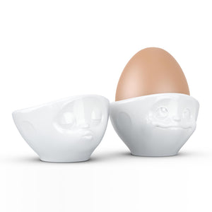 Set of two egg cups in white from the TASSEN product family of fun dishware by FIFTYEIGHT Products. Set features two egg cups in white, featuring 'kissing' and 'dreamy' facial expressions. Dishwasher and microwave safe bowls. Shipped in exclusively designed gift box.