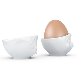 Set of two egg cups in white from the TASSEN product family of fun dishware by FIFTYEIGHT Products. Set features two egg cups in white, featuring 'Oh please' and 'tasty' facial expressions. Dishwasher and microwave safe bowls. Shipped in exclusively designed gift box.