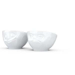 Set of two egg cups in white from the TASSEN product family of fun dishware by FIFTYEIGHT Products. Set features two egg cups in white, featuring 'Happy' and 'Hmpff' facial expressions. Dishwasher and microwave safe bowls. Shipped in exclusively designed gift box.