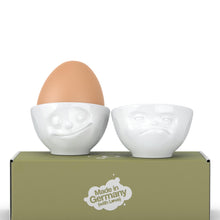 Load image into Gallery viewer, Set of two egg cups in white from the TASSEN product family of fun dishware by FIFTYEIGHT Products. Set features two egg cups in white, featuring &#39;Happy&#39; and &#39;Hmpff&#39; facial expressions. Dishwasher and microwave safe bowls. Shipped in exclusively designed gift box.
