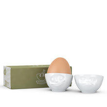 Load image into Gallery viewer, Set of two egg cups in white from the TASSEN product family of fun dishware by FIFTYEIGHT Products. Set features two egg cups in white, featuring &#39;Happy&#39; and &#39;Hmpff&#39; facial expressions. Dishwasher and microwave safe bowls. Shipped in exclusively designed gift box.
