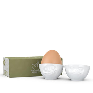 Set of two egg cups in white from the TASSEN product family of fun dishware by FIFTYEIGHT Products. Set features two egg cups in white, featuring 'Happy' and 'Hmpff' facial expressions. Dishwasher and microwave safe bowls. Shipped in exclusively designed gift box.